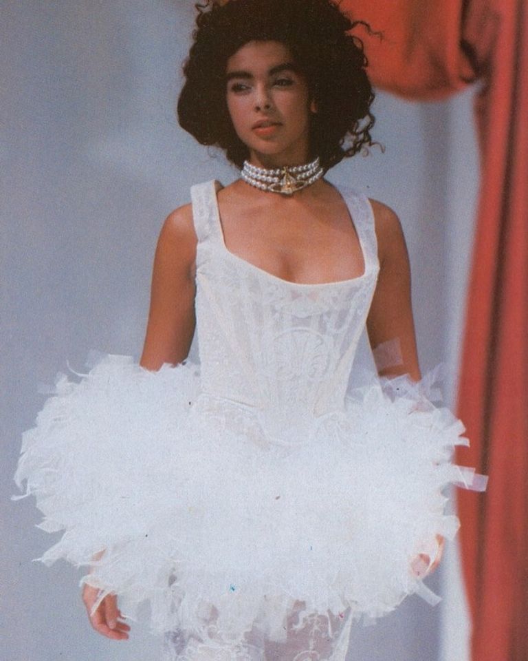 A model on the runway in a ballerina dress and pearl necklace.
